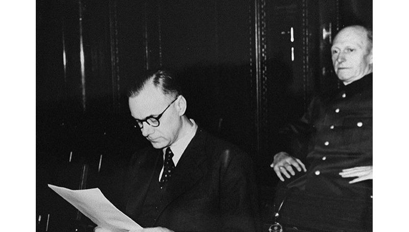 Alfred Rosenberg (L) reads a document during the Nuremberg war crimes tribunal in 1946.