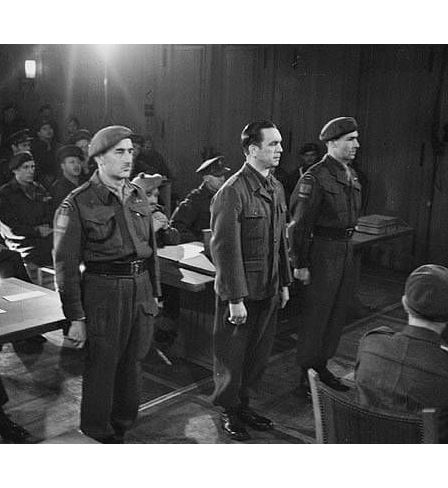 SS Brigadefuhrer Kurt Meyer standing in court with escorts Major Arthur Russel (left) and Captain Elton D. McPhail (right) in Aurich, Germany. 10 December 1945. 