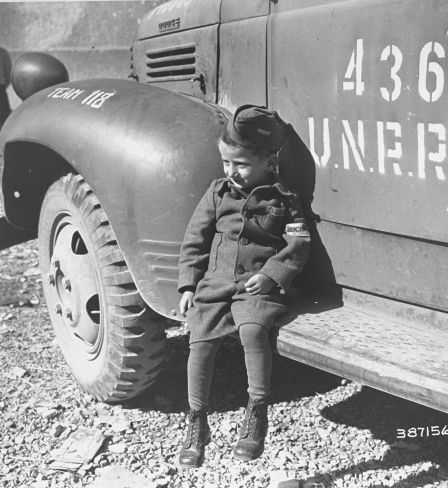 Joseph Schleifstein, survivant de Buchenwald âgé de quatre ans, est assis sur le marchepied d'un camion de l'UNRRA peu après la libération du camp. 1945. National Archives and Records Administration, College Park, Source Record ID: 111-SC-387156