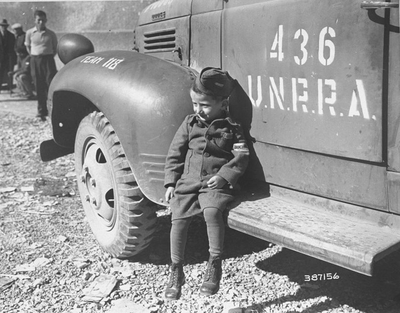 Joseph Schleifstein, survivant de Buchenwald âgé de quatre ans, est assis sur le marchepied d'un camion de l'UNRRA peu après la libération du camp. 1945. National Archives and Records Administration, College Park, Source Record ID: 111-SC-387156