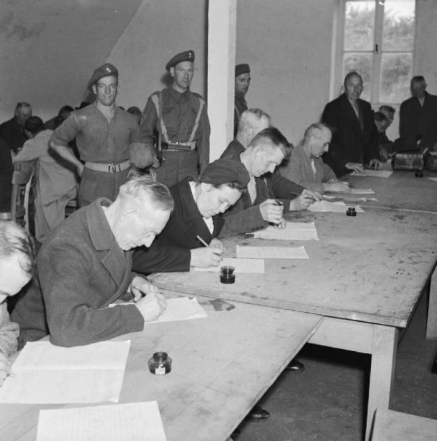  Suspected Nazis fill in a questionnaire about their political activities in a detention centre near Hamburg run by the British Army. Imperial War Museum Collection.