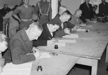  Suspected Nazis fill in a questionnaire about their political activities in a detention centre near Hamburg run by the British Army. Imperial War Museum Collection.