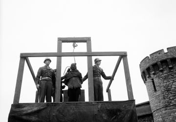 The noose is tightened around the hooded neck of Karl Willig, a nurse at the Hadamar Medical Institute, Germany, before the trap is sprung in the courtyard of the Bruchsal Prison, 14 March 1946. Willig and two others had been found guilty of murdering some 300 Polish and Russian prisoners of war by means of lethal injection. The other two were hanged the same morning.