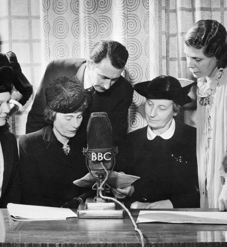 Alors que les employés hommes de la British Broadcasting Company entrent dans les forces armées, les femmes prennent à la BBC les postes de producteur, rédacteur en chef, présentateur, annonceur, créateur d’effets sonores et assurent une part importante et croissante de l’ensemble des émissions de divertissement. Personnes participant à la diffusion de la BBC à Londres, le 15 janvier 1943, pendant Answering you, émission hebdomadaire diffusée sur les ondes courtes aux États-Unis et au Canada: (de gauche à droite) Mme Mary Adams, productrice; Colin Wills, présentateur; et Mme Archer, femme au foyer et travailleuse de guerre; (assis de gauche à droite) Mme Gardner, intendante de la garderie Brook Green; Mme Margaret Biddle, épouse de l’ambassadeur américain auprès des gouvernements alliés à Londres, et Mme Florence Horsbrugh, membre du Parlement, secrétaire parlementaire du ministre de la Santé.