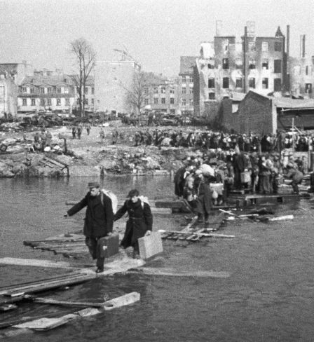 Residents of Königsberg cross the river using a wooden bridge as they return home on 9 April 1945