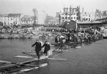 Residents of Königsberg cross the river using a wooden bridge as they return home on 9 April 1945