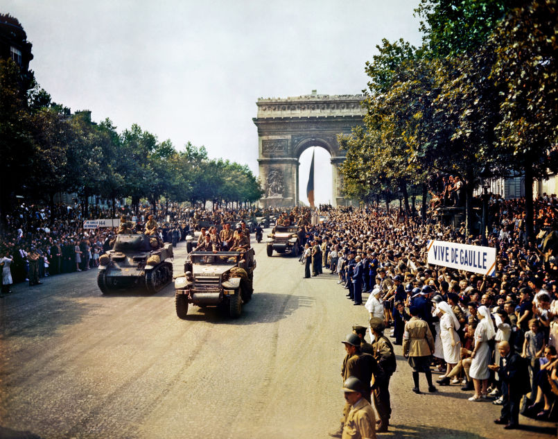 Crowds of French patriots line the Champs Elysees watch as Free French tanks and half-tanks of General Leclerc's 2nd Armoured Division pass through the Arc de Triomphe during the liberation of Paris on 26 August 1944. Among the crowd can be seen banners in support of Charles de Gaulle.