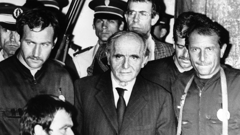 French policemen lead a handcuffed Klaus Barbie out of the courtroom in Lyon, after he was convicted on July 4, 1987, of crimes against humanity when he was Gestapo chief in this city. He was sentenced to life in prison