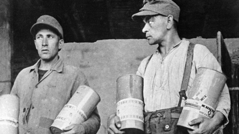 Des gardiens du camp de Majdanek montrent des  boîtes contenant du gaz toxique Zyklon-B (ils ont été pendus suite à la décision du tribunal en 1944 à Lublin, en Pologne).