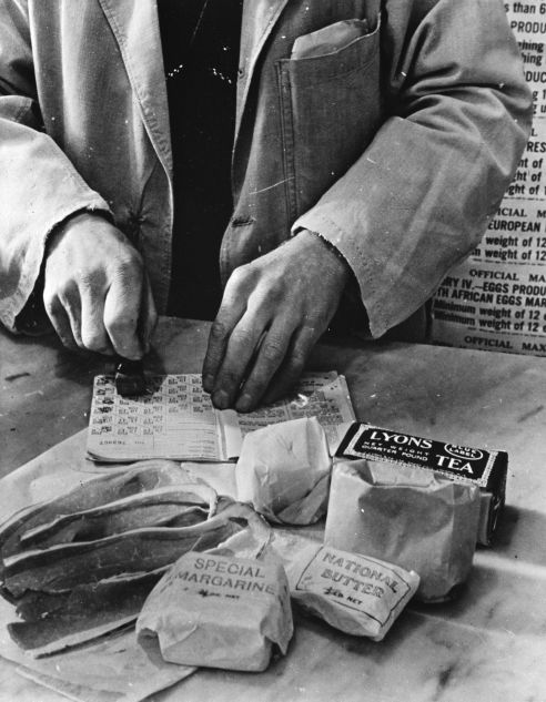 Rationnement des civils au Royaume-Uni: un vendeur tamponne des coupons alimentaires dans un carnet d'alimentation d'une ménagère britannique, 1943