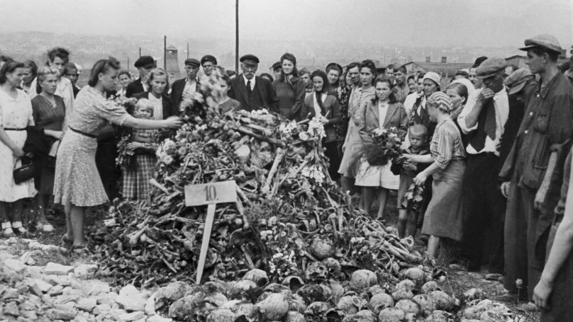 People lay flowers near human remains at the Majdanek concentration camp after it was liberated