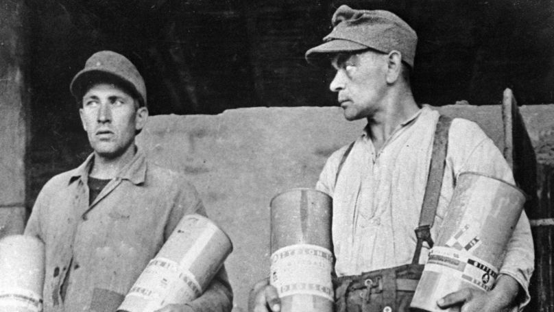 Executioners hold canisters with Ziklon-B poisonous gas used at the Majdanek concentration camp